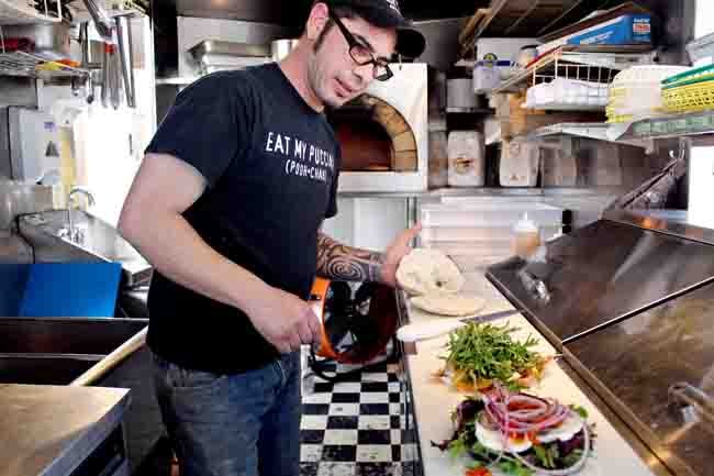 Lucky building a puccia in the trailer, wood-fired oven behind him